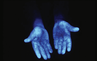 Blue light shining on hands revealing germs.