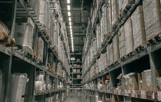 Aisle view in warehouse with boxes on shelves.