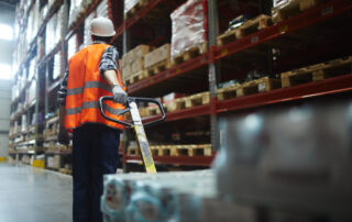 man pulling forklift in warehouse